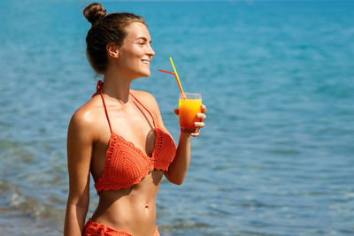 Beautiful woman holding drink at beach