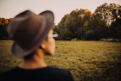 Rear view of man standing by tree on field