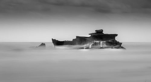 Built structure in sea against cloudy sky