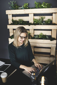 Woman using mobile phone while sitting on table