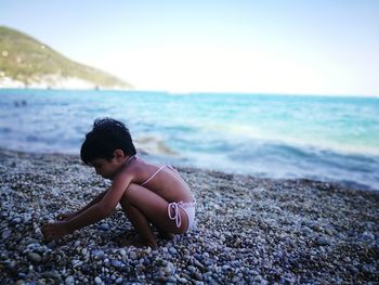 Girl playing with pebbles at beach