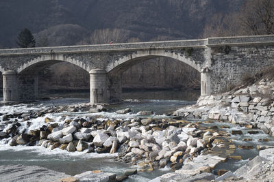 Arch bridge over river against mountain