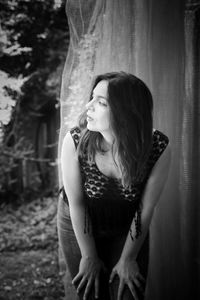 Young woman looking down while standing against blurred background