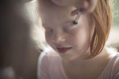 Cropped hand of person applying eyeshadow to girl