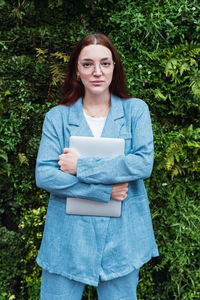 Confident businesswoman holding laptop and looking at camera