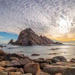 Rocks on sea shore against sky during sunset