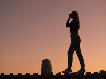 Silhouette man standing against orange sky