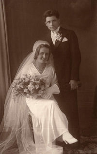 Man and woman wearing mask standing against wall