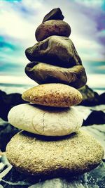 Stack of pebbles in sea against sky