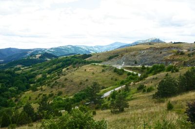 Scenic view of green landscape and mountains against sky