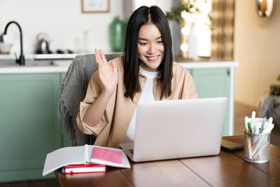 Portrait of young woman using laptop on table