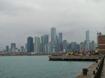 Sea by modern buildings against sky in city