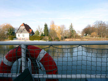 House by swimming pool by lake against sky