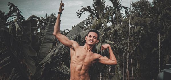 Portrait of young man standing by palm trees