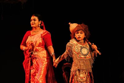 Portrait of woman standing against black background