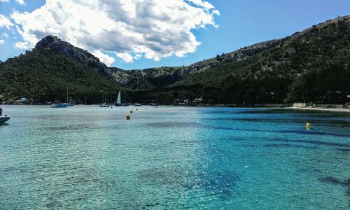 Scenic view of sea and mountains against blue sky