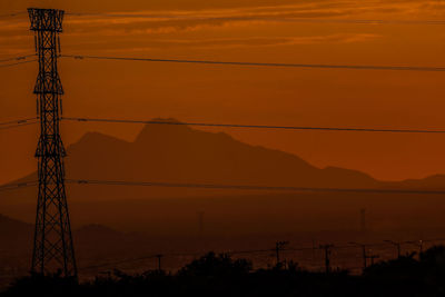 Low angle view of electricity pylon against sky during sunset