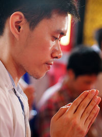 Side view of young man praying in temple