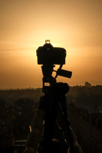 Silhouette tripod against sky during sunset