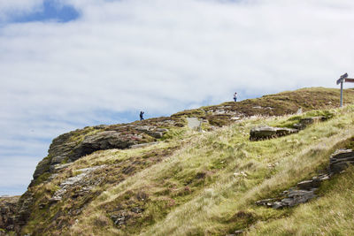 People on hill against sky