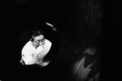 High angle view of man smoking cigarette seen from hole in wall