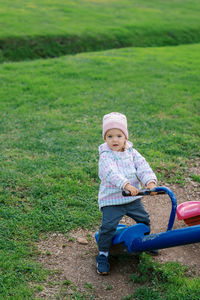 Full length of boy sitting on grassy field