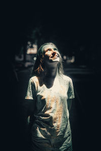 Portrait of young woman standing against black background