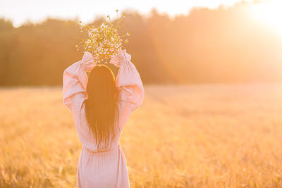 Midsection of woman standing by plant on field