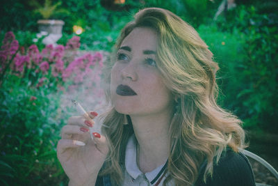 Portrait of young woman smoking cigarette outdoors