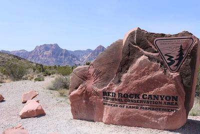 Information sign on desert against sky