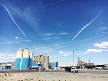 Pick-up truck on road by industrial buildings against blue sky