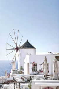 Traditional windmill in city by sea against clear sky