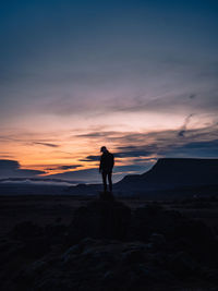 Silhouette man standing on beach against sky during sunset