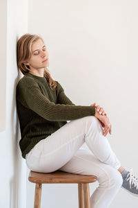 Minimal light and airy interior design. attractive young woman in white jeans and green sweater sitt