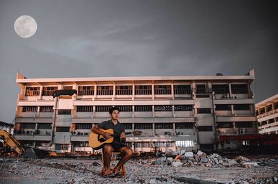 Portrait of woman sitting against built structure