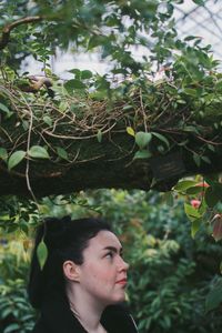 Woman looking away against trees