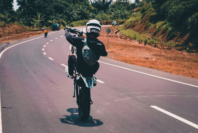 Rear view of man riding bicycle on road