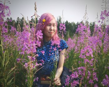Beautiful young woman standing by flowers