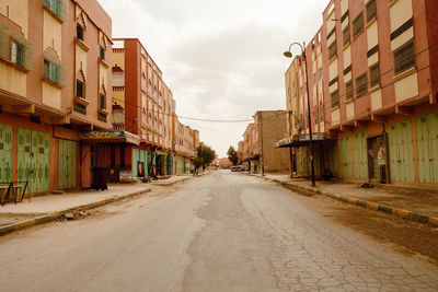 Empty road amidst buildings in city