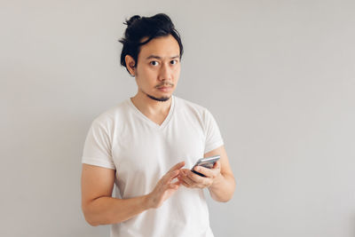 Young man using smart phone against white background