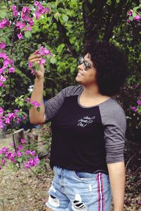 Full length of woman standing by pink flowering plants