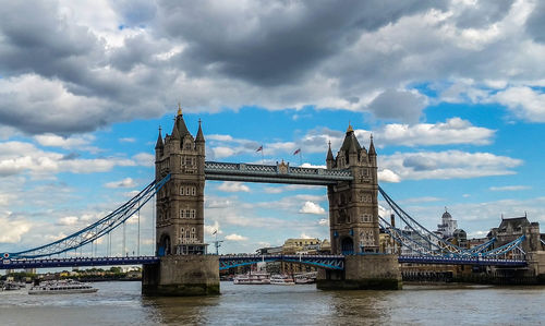 Low angle view of tower bridge over thames river against cloudy blue sky in city