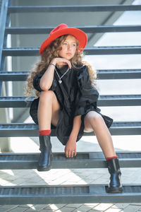 Portrait of young woman wearing hat while standing on railing