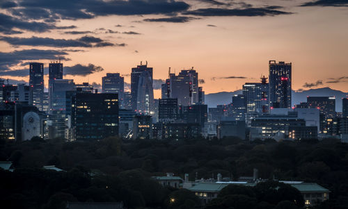 View of illuminated buildings in city against sky during sunset