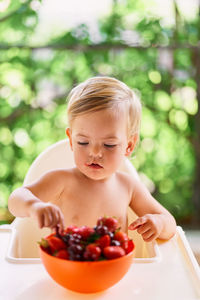 Midsection of shirtless man with fruits in bowl