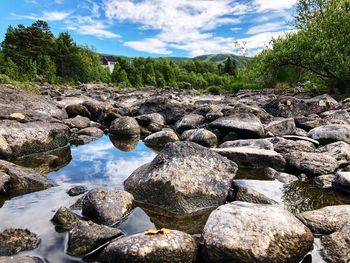 Rocks by stream against sky