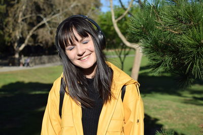 Portrait of smiling young woman standing against plants