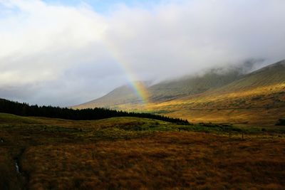 Scenic view of rainbow over landscape against sky