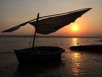 Sailboats moored on sea against sky during sunset