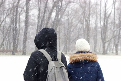 Rear view of woman and man walking on snow covered land